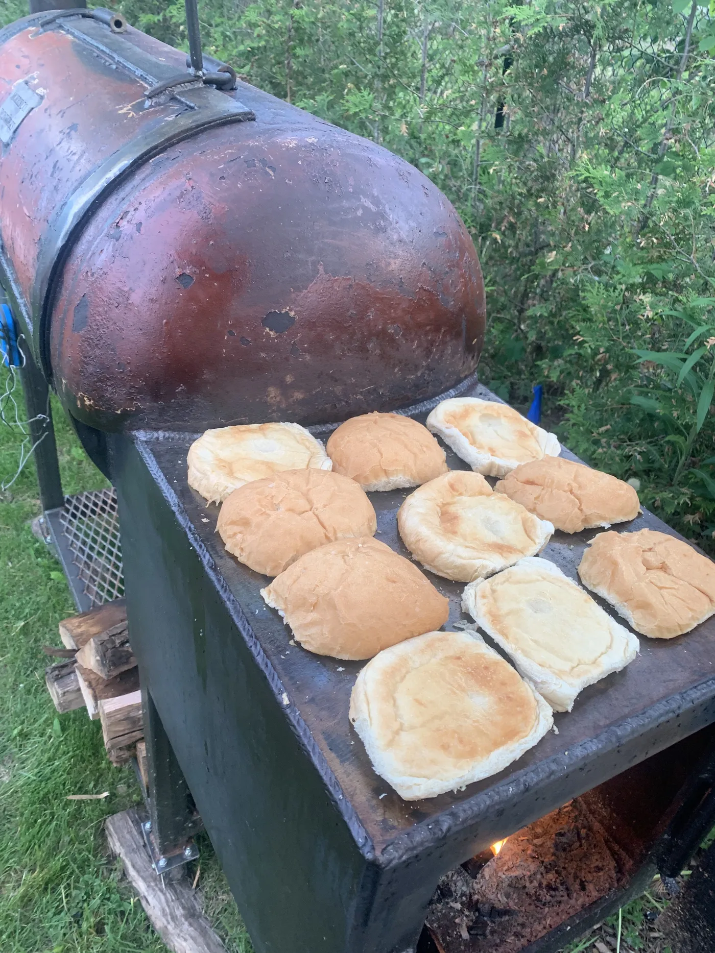 Burger buns toasting on top of the offset smoker's firebox in the evening